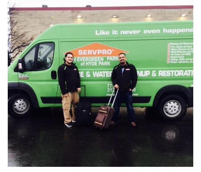 Two SERVPRO employees standing with suitcases for a mitigation skills class