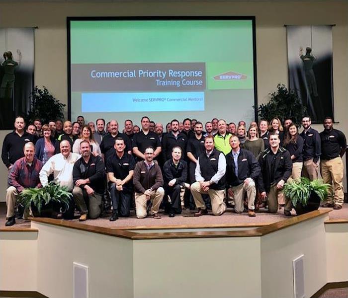 A large group of people in front of a projector screen that says commercial priority response