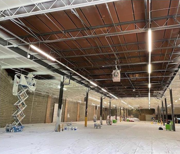 Large warehouse with white floor covering and an employee working on a lift