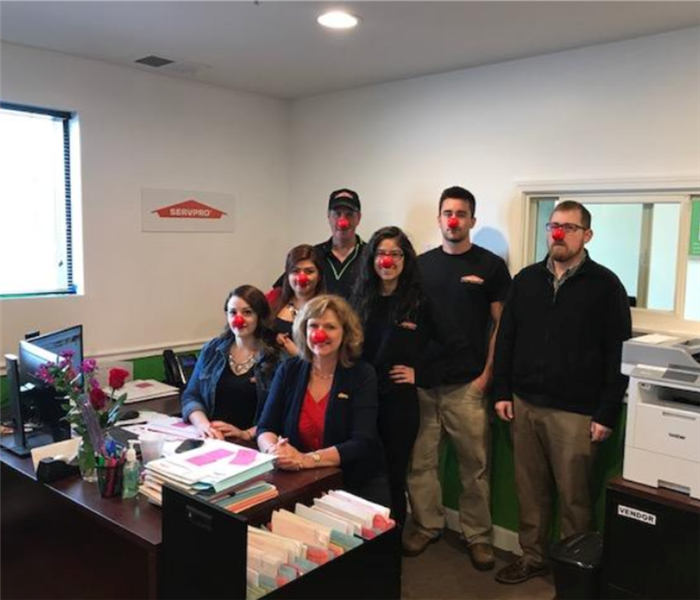 People in a office with red noses on the faces 