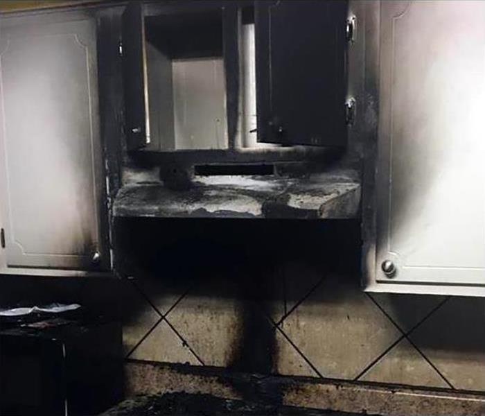 A stovetop charred by a fire with soot and smoke damage