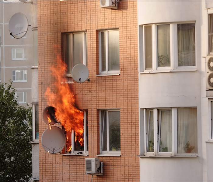 fire billowing out of the window of an apartment