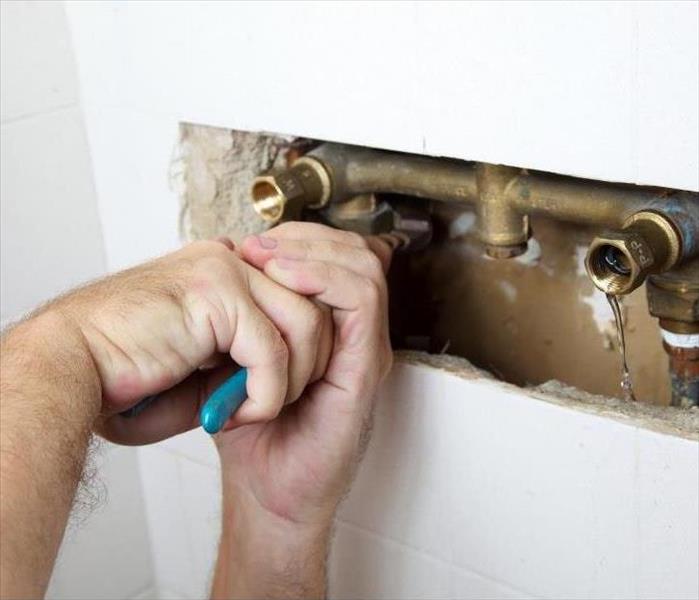 plumber turning wrench to fix leak in shower