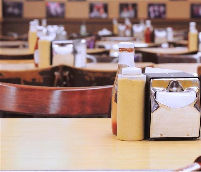 A diner with mustard, ketchup, and napkin dispenser on tables