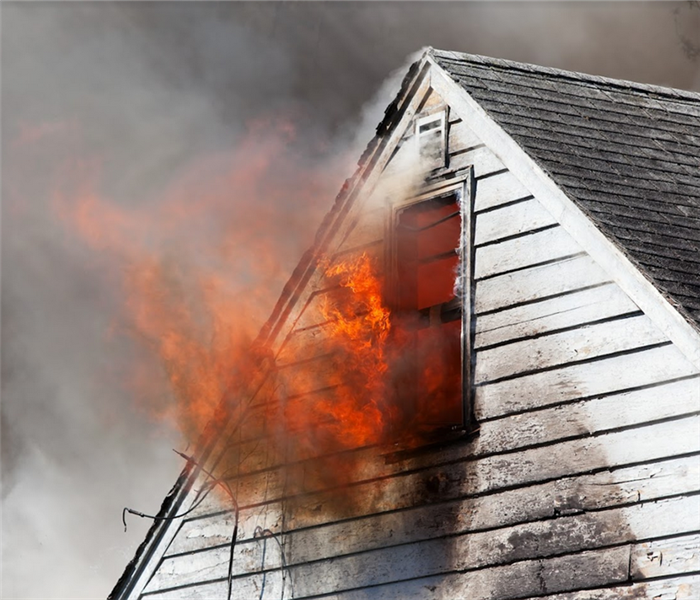 the top of a house with the window on fire with fire and smoke billowing from the house